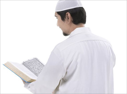 عکس با کیفیت از مرد مسلمان در حال خواندن کتاب قرآن