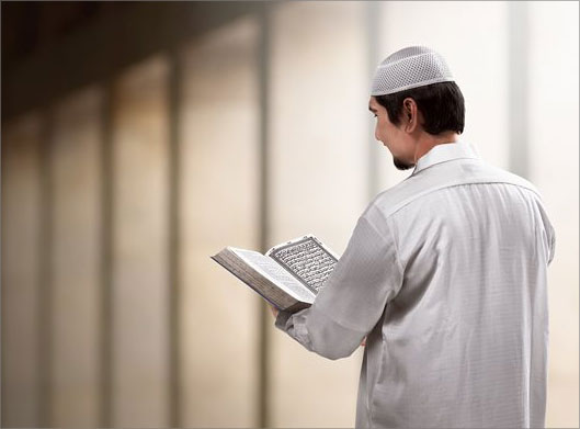 تصویر با کیفیت از مرد مسلمان ایستاده در حال تلاوت قرآن