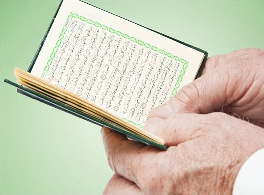عکس با کیفیت از کتاب دعا و قرآن در دست مرد مسلمان