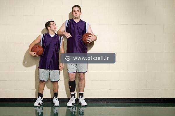 عکس با کیفیت از دو بازیکن قد بلند بسکتبال با توپ در دست