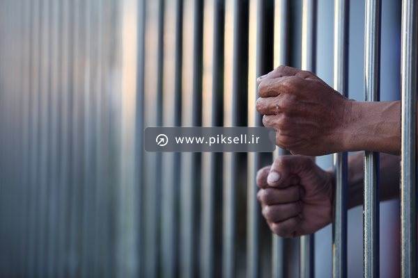 عکس با کیفیت از دستان مرد پشت میله های زندان و اسیر