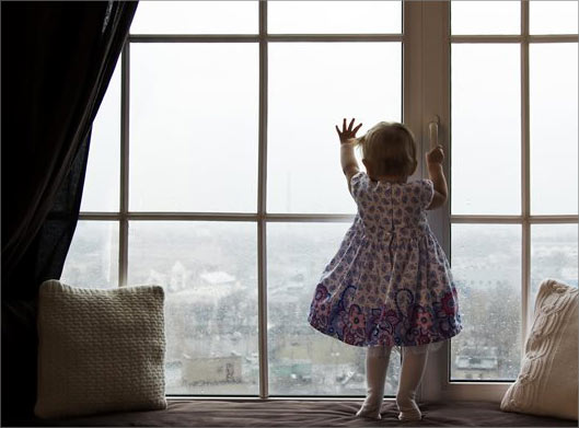 عکس با کیفیت از دختربچه پشت پنجره و نمای شهر