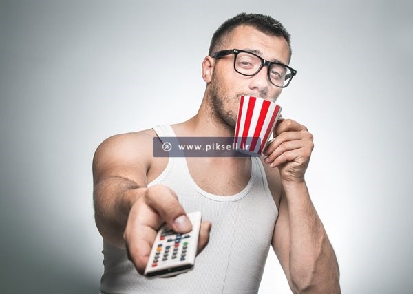 عکس با کیفیت از خوردن نوشیدنی و کنترل تلویزیون در دست