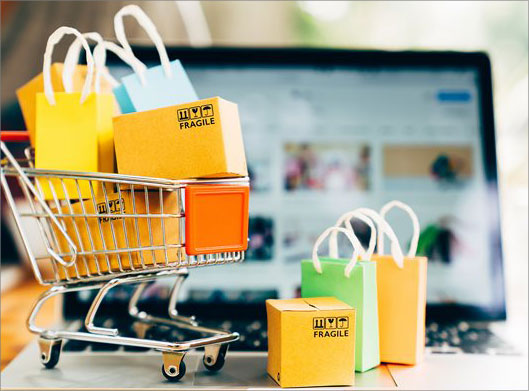 عکس با کیفیت از سبد و بگ های خرید روی لپ تاپ با پس زمینه فروشگاه آنلاین