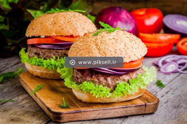 عکس با کیفیت از دو همبرگر روی تخته آشپزی