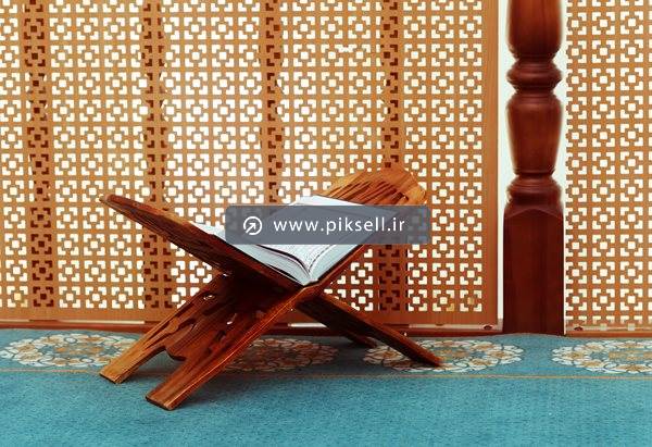 عکس با کیفیت از رحل و قرآن با پس زمینه پنجره چوبی