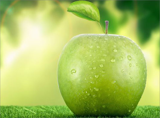 عکس با کیفیت از سیب سبز و پس زمینه برگ سبز