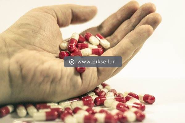 عکس با کیفیت از کپسولهای مسکن در دست