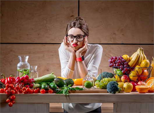 عکس با کیفیت از دختر جوان و میز میوه و سبزی و صیفی
