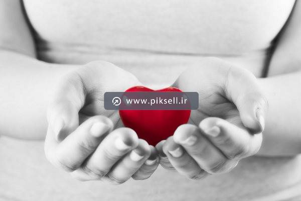 تصویر با کیفیت سیاه و سفید از قلب قرمز سه بعدی در دست