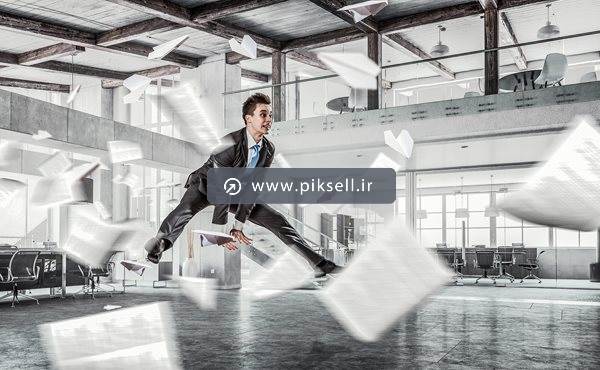 عکس با کیفیت از مرد پریده در هوا و کاغذهای پاشیده شده در فضا
