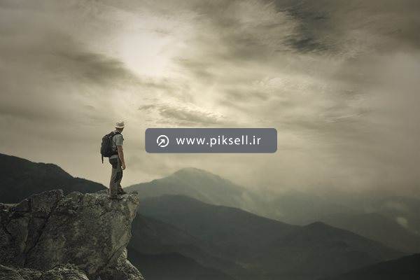 تصویر با کیفیت از مرد صخره نورد ایستاده روی کوه