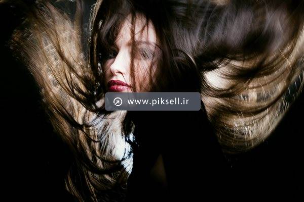 عکس با کیفیت از دختر جوان با موهای پریشان در هوا