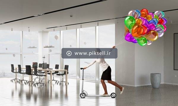 عکس با کیفیت از اسکوتر بازی زن جوان با بادکنک در شرکت