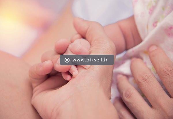 تصویر با کیفیت از دست نوزاد در دست مادر