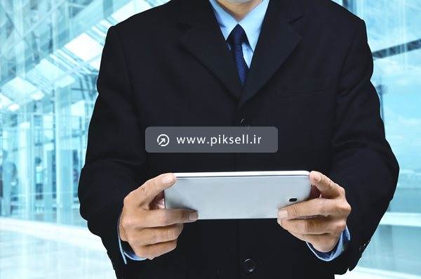 تصویر با کیفیت از مرد کت و شلواری در حال کار با گوشی و تبلت